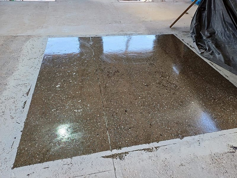 Área de teste de lapidação em piso de concreto antigo, com agregado exposto e brilho, ao lado do concreto original sem tratamento
