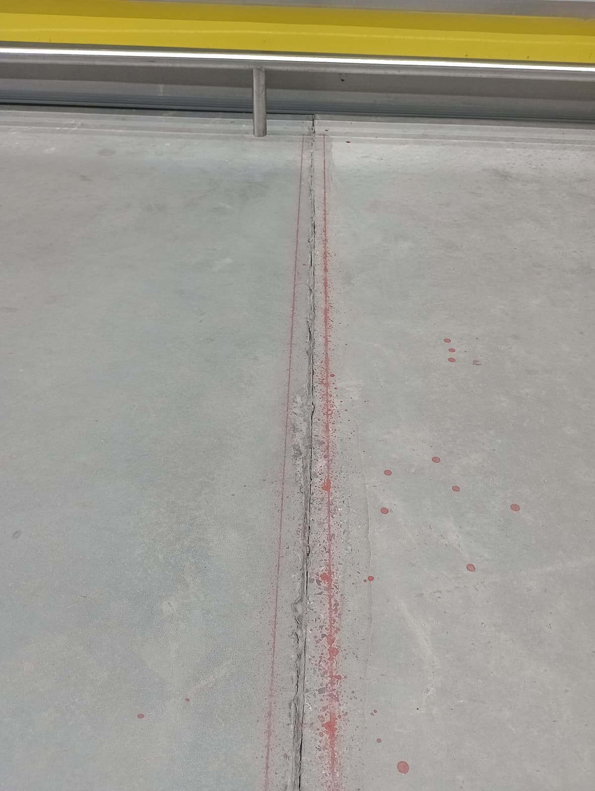 Junta de piso com bordas quebradas marcada em vermelho no corredor de congelados de um atacadista, ao lado dos expositores