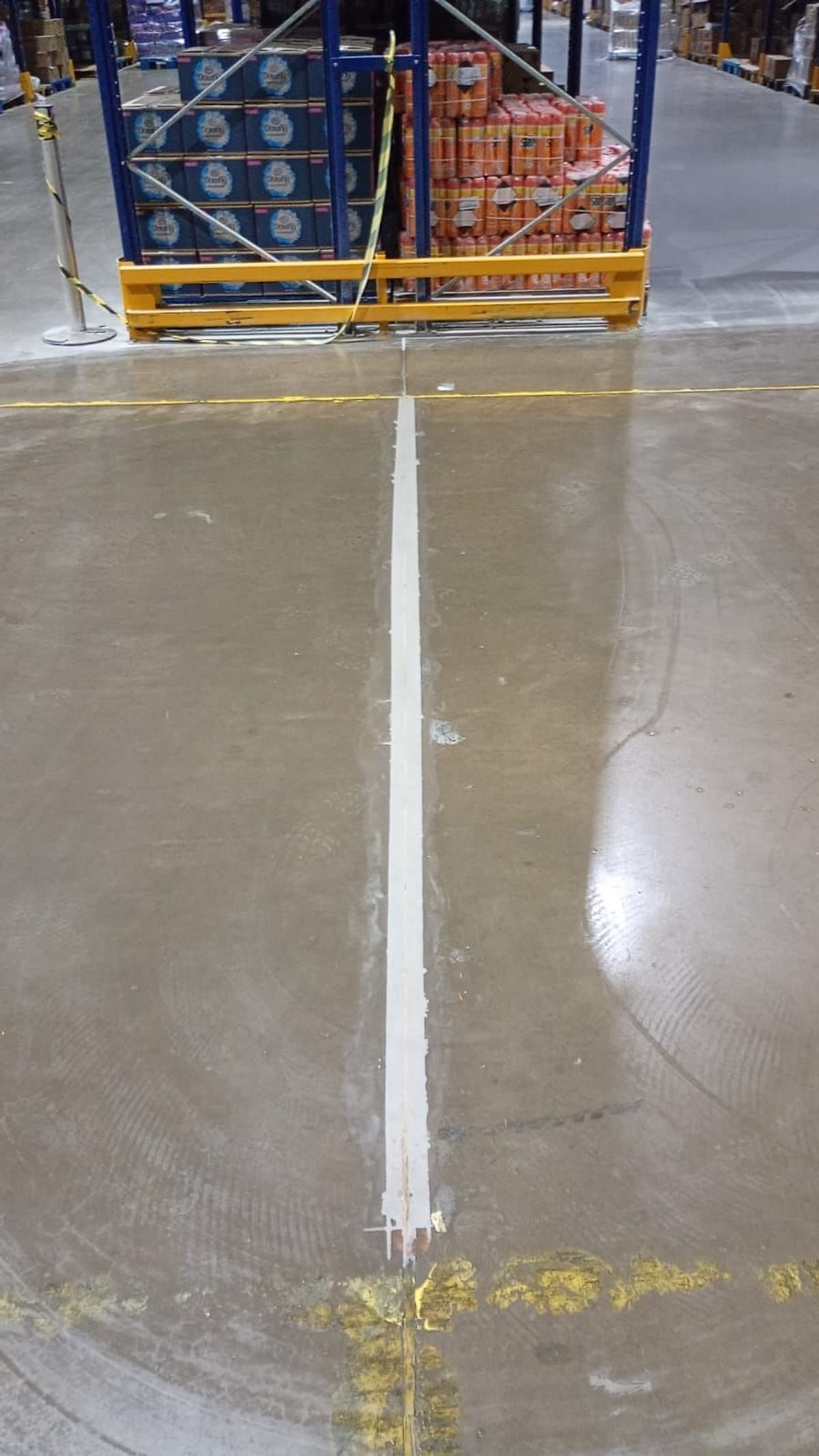 Lábio polimérico claro entre estruturas porta-paletes, nivelado com o piso