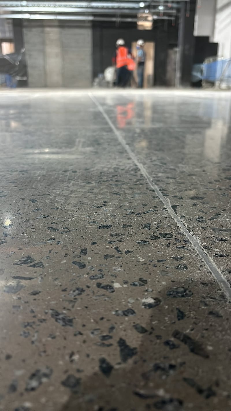 Junta serrada em piso de concreto lapidado com agregado exposto, vista rente ao chão