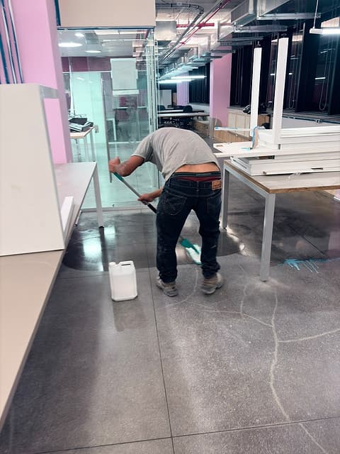 Profissional de costas aplicando o acabamento no granilite junto às bancadas fixas