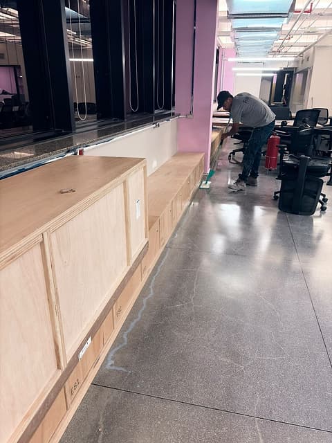 Profissional aplicando o acabamento ao longo de um móvel fixo junto à janela