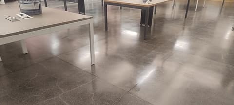 Piso de granilite brilhante refletindo as luminárias entre as mesas do escritório