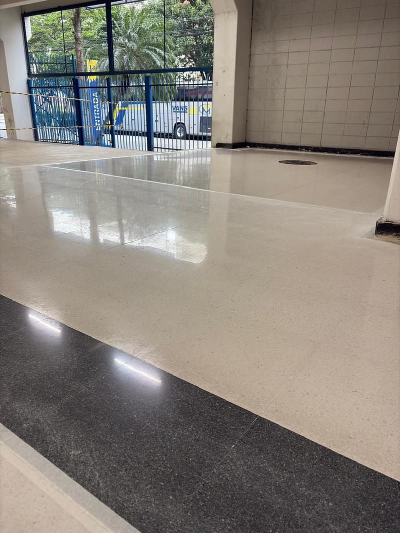Granilite branco polido com juntas de dilatação e faixa de granilite preto, diante de fachada envidraçada