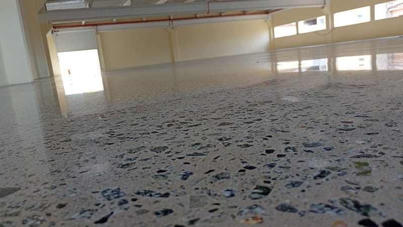 Detalhe do agregado exposto no piso de concreto lapidado da Cliptech, em São Bernardo do Campo, com as janelas do salão refletidas na superfície