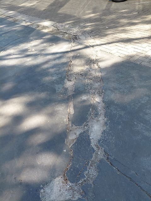 Junta de piso com bordas quebradas e material solto na área externa da loja
