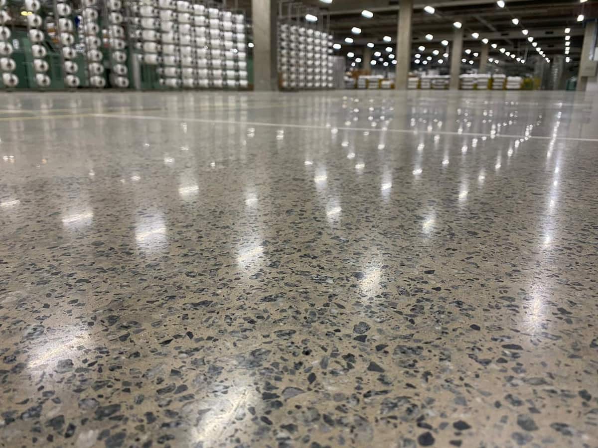 Piso de concreto lapidado em centro de distribuição refletindo as luminárias do galpão