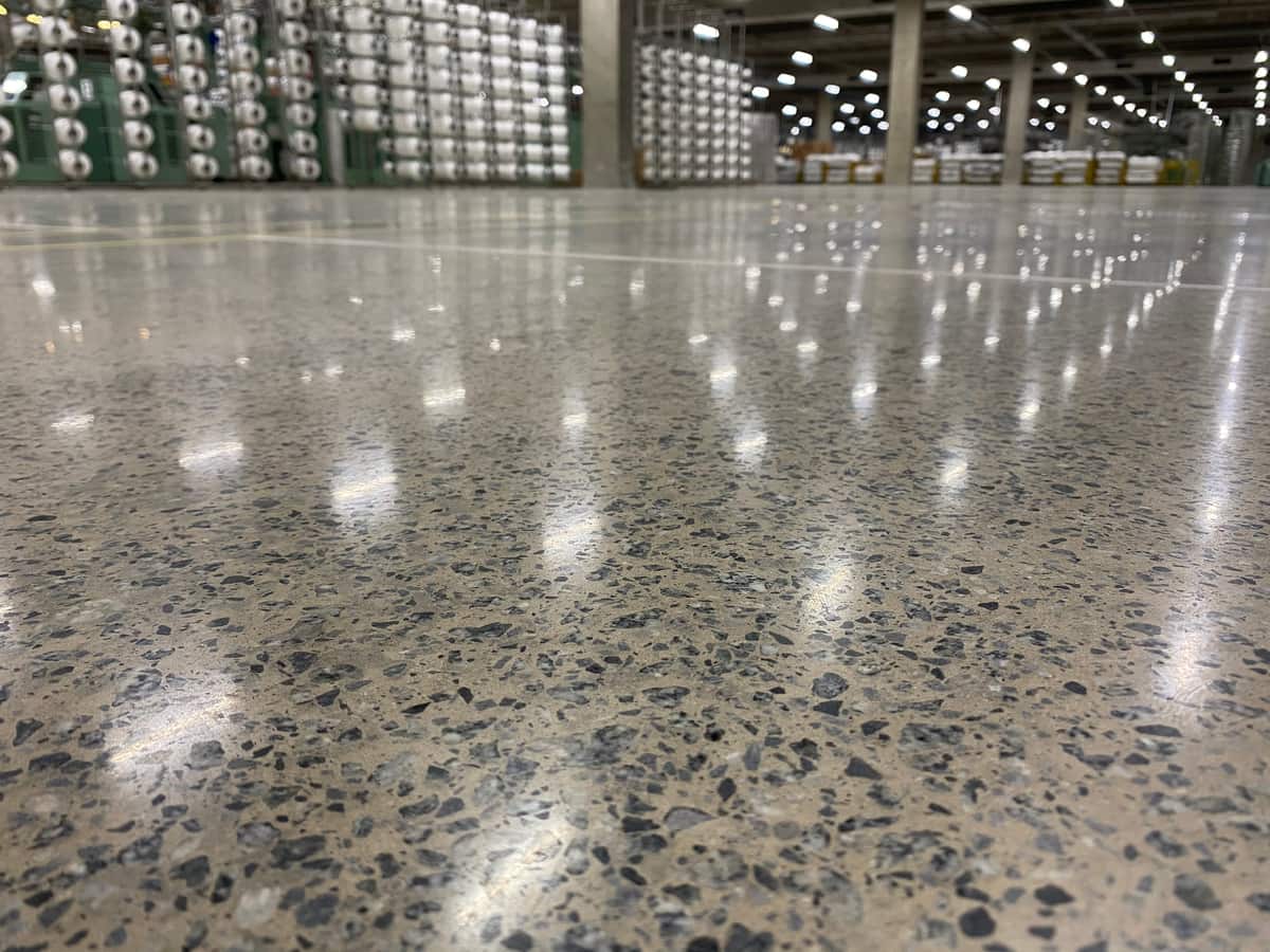 Piso de concreto lapidado em centro de distribuição refletindo as luminárias