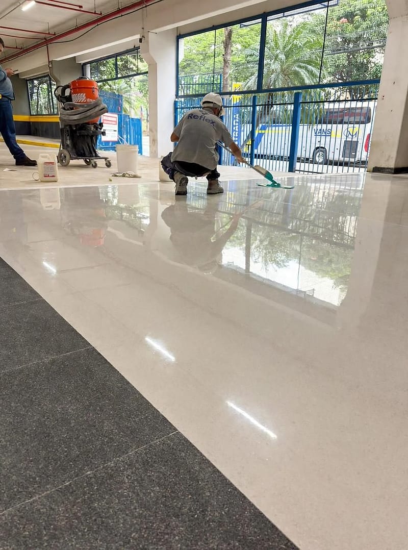 Técnico da Reflex aplica selador sobre piso de granilite polido em área de grande circulação