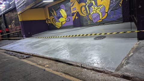 Frente da loja com o revestimento cinza aplicado e a área isolada por fita zebrada