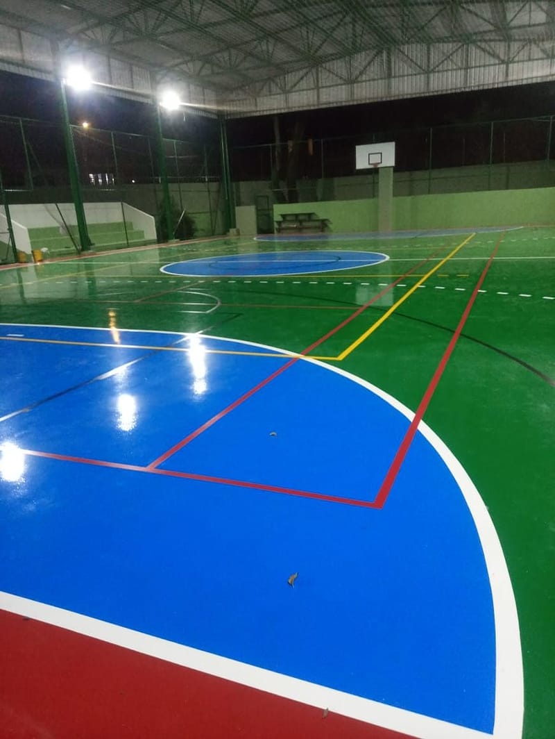Área de basquete azul com linhas vermelhas e brancas em quadra coberta de piso brilhante