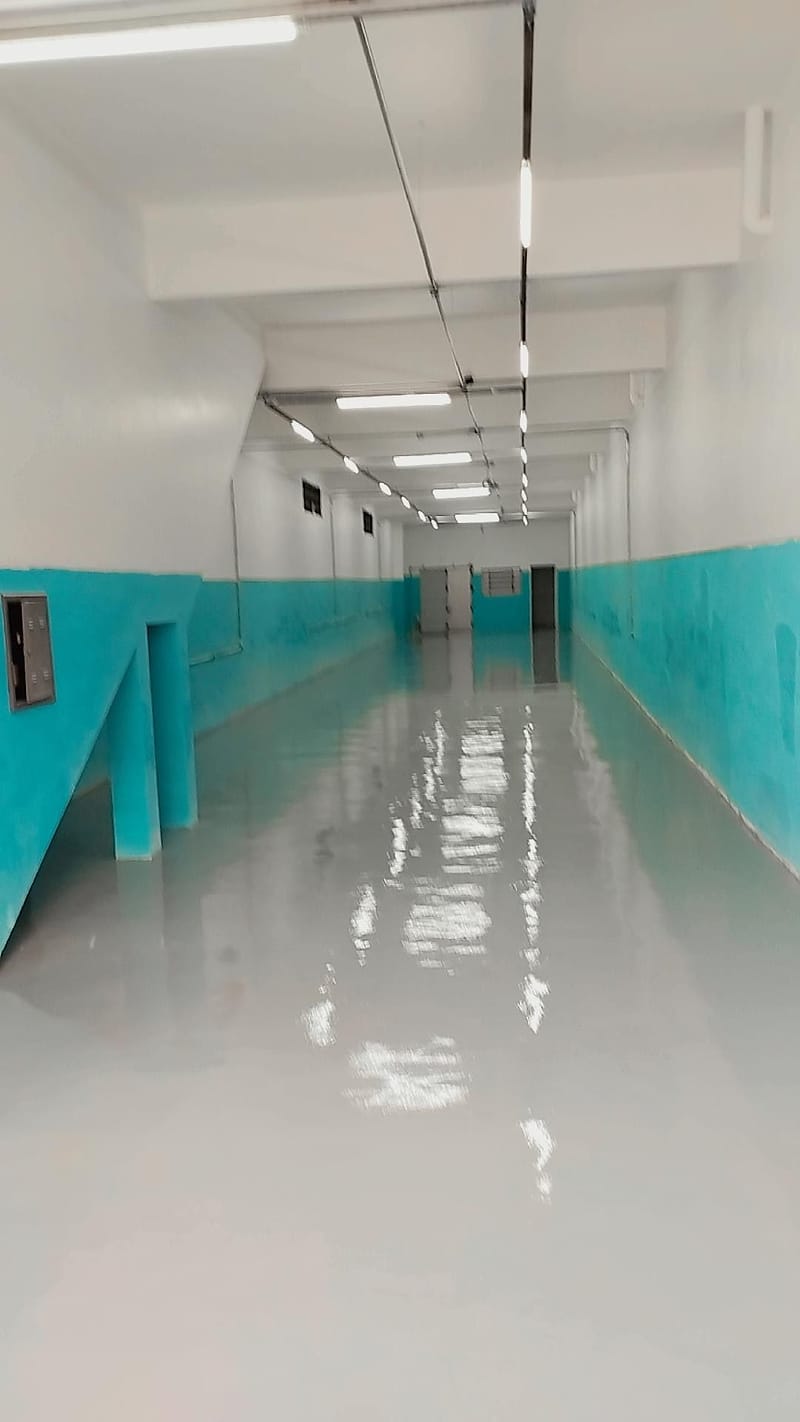 Corredor técnico comprido com revestimento epóxi cinza claro brilhante e meia parede verde-água